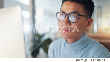 Asian man at computer, glasses and reflection, thinking and reading email, review or article at digital agency. Internet, research and businessman at tech startup with report, networking or feedback. Asian man at computer, glasses and reflection, thinking and reading email, review or article at digital agency. Internet, research and businessman at tech startup with report, networking or feedback. 112302412