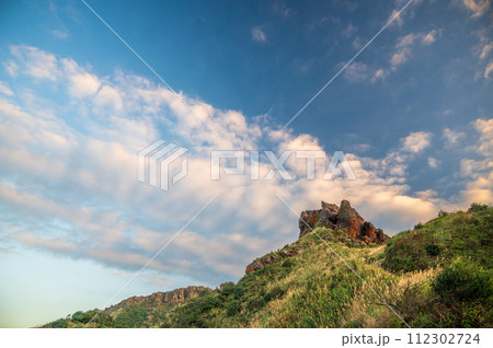 Strange mountain top silhouette and blue sky and white clouds. 112302724