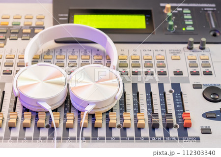 white headphone on audio mixing console. music background, recording concept white headphone on audio mixing console. music background, recording concept 112303340
