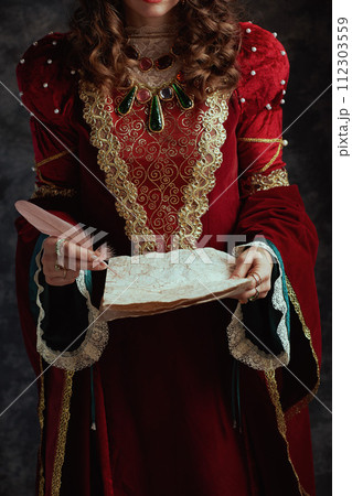 Closeup on medieval queen in red dress with parchment 112303559