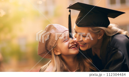 Happy dark-skinned, black, African-American mother hugging her student daughter in a cap, graduate cap near an educational institution. Happy dark-skinned, black, African-American mother hugging her student daughter in a cap, graduate cap near an educational institution. 112304484