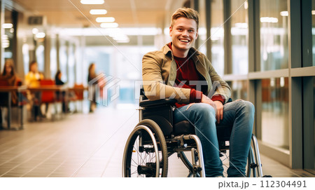 Happy, smiling young guy student in a wheelchair in the foyer of an educational institution. 112304491