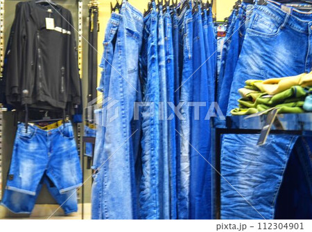 Row of hanged blue jeans in a shop. Clothes store. Shopping in fashion mall. Garments on hangers Row of hanged blue jeans in a shop. Clothes store. Shopping in fashion mall. Garments on hangers 112304901