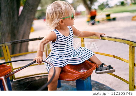 Little girl in sunglasses sits on a carousel with her back turned. High quality photo Little girl in sunglasses sits on a carousel with her back turned. High quality photo 112305745