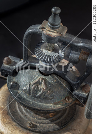 Detail of Antique coffee bean original grinder metal shake wheel with hand crank on dark background. Detail of Antique coffee bean original grinder metal shake wheel with hand crank on dark background. 112306209