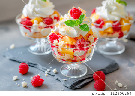 Vanilla peach dessert or melba ice cream with peach fruits. Colorful assortment of fruit salad topped with whipped cream 112306264