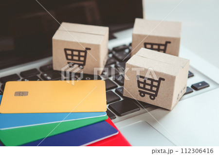 Shopping online. Credit card and cardboard box with a shopping cart logo on laptop keyboard. Shopping service on The online web. offers home delivery Shopping online. Credit card and cardboard box with a shopping cart logo on laptop keyboard. Shopping service on The online web. offers home delivery 112306416