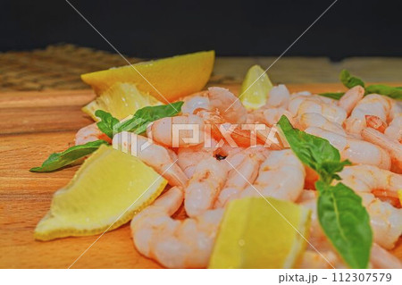 Cooked and peeled prawns with slices of lemon and leaves of basil on chopping board. Food photography. Healthy food. Bio recipe 112307579