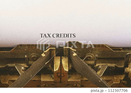Closeup on vintage typewriter. Front focus on letters making TAX CREDITS text. Business concept image with retro office tool Closeup on vintage typewriter. Front focus on letters making TAX CREDITS text. Business concept image with retro office tool 112307706