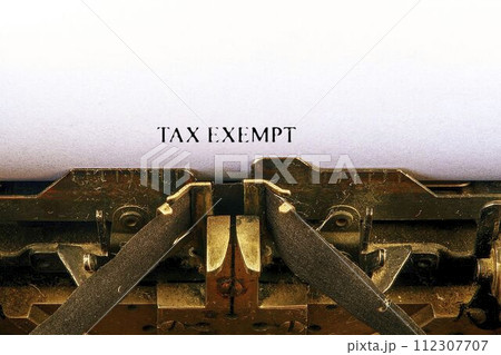 Closeup on vintage typewriter. Front focus on letters making TAX EXEMPT text. Business concept image with retro office tool Closeup on vintage typewriter. Front focus on letters making TAX EXEMPT text. Business concept image with retro office tool 112307707