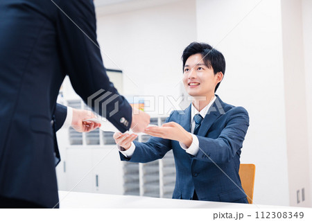 窓口で紙の書面の取り交わしをするビジネスマン 112308349