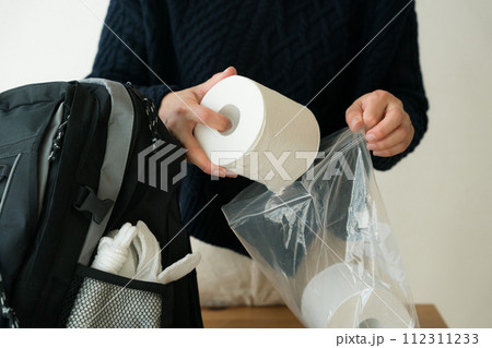 防災リュックにトイレットペーパーを入れる女性 112311233