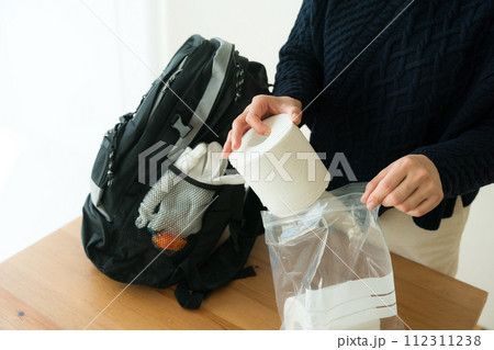 防災リュックにトイレットペーパーを入れる女性 112311238