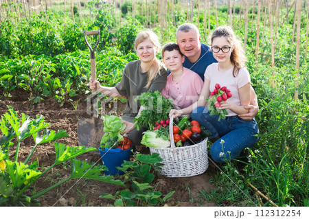 Happy family with fresh harvest in backyard garden 112312254