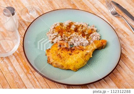 Prepared buckwheat porridge with piece of fried chicken is served on large white platter Prepared buckwheat porridge with piece of fried chicken is served on large white platter 112312288