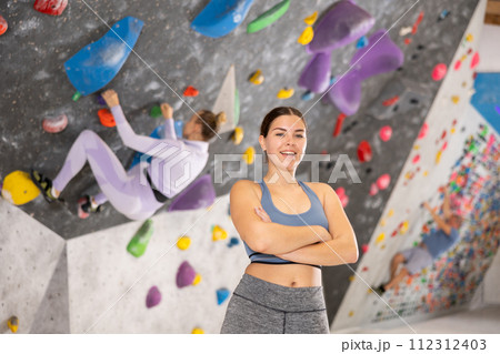 Portrait of slender smiling woman climber on background of climbing wall 112312403