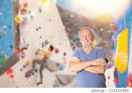 Adult man posing on climbing wall Adult man posing on climbing wall 112312483