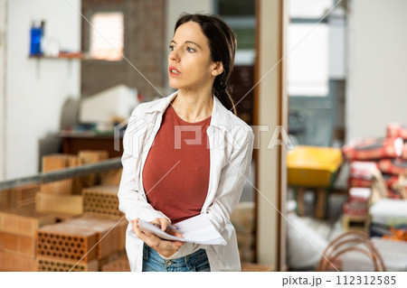 Interested brunette making notes while planning home renovation 112312585