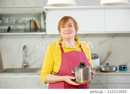 Adult woman in apron posing with saucepan 112312683