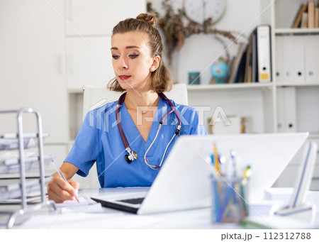 Woman doctor sitting at workplace with computer in her office 112312788