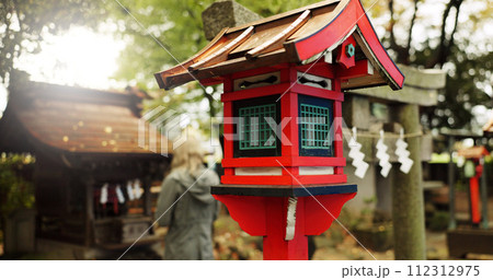 Japan, nature and wooden lantern in Kyoto with trees, tourist and woman with torii gate. Architecture, japanese culture and shinto shrine in woods with sculpture, religion memorial and monument Japan, nature and wooden lantern in Kyoto with trees, tourist and woman with torii gate. Architecture, japanese culture and shinto shrine in woods with sculpture, religion memorial and monument 112312975
