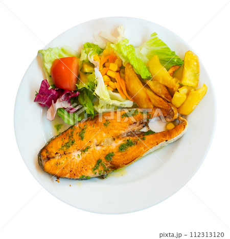 On plate, slice of fried salmon garnished with French fries and salad of fresh vegetables 112313120