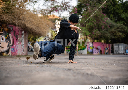 An active, professional Asian male breakdancer or hiphop dancer is performing on the street. 112313241