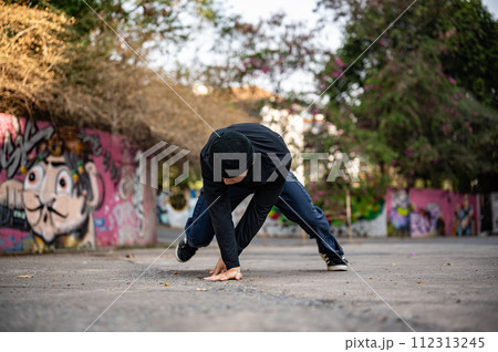 A talented and energetic Asian male hiphop dancer in fashionable clothes is dancing on the street. A talented and energetic Asian male hiphop dancer in fashionable clothes is dancing on the street. 112313245