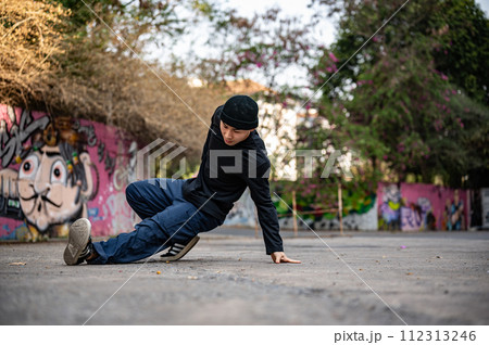 A talented and energetic Asian male hiphop dancer in fashionable clothes is dancing on the street. A talented and energetic Asian male hiphop dancer in fashionable clothes is dancing on the street. 112313246