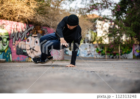 A talented and energetic Asian male hiphop dancer in fashionable clothes is dancing on the street. A talented and energetic Asian male hiphop dancer in fashionable clothes is dancing on the street. 112313248