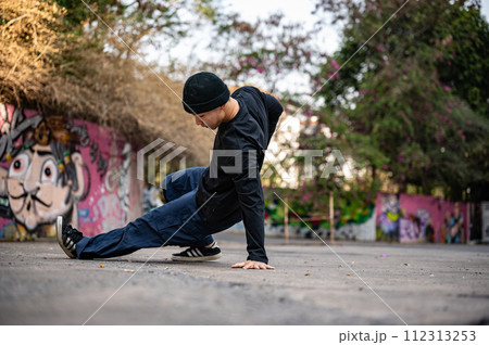 A cool Asian male breakdancer is performing his breakdance on the street, enjoying with the rhythm. A cool Asian male breakdancer is performing his breakdance on the street, enjoying with the rhythm. 112313253