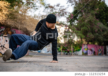 A cool, stylish Asian male hiphop dancer is dancing on the street in the city, practicing b-boy. A cool, stylish Asian male hiphop dancer is dancing on the street in the city, practicing b-boy. 112313254