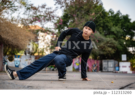 A cool, stylish Asian male hiphop dancer is dancing on the street in the city, practicing b-boy. A cool, stylish Asian male hiphop dancer is dancing on the street in the city, practicing b-boy. 112313260