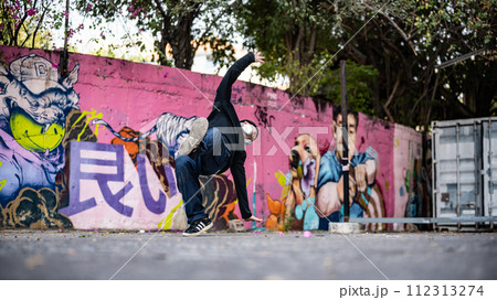An energetic, professional Asian male hiphop dancer is practicing his breakdance on the street. An energetic, professional Asian male hiphop dancer is practicing his breakdance on the street. 112313274