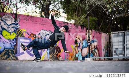 An energetic, professional Asian male hiphop dancer is practicing his breakdance on the street. An energetic, professional Asian male hiphop dancer is practicing his breakdance on the street. 112313275
