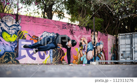 An energetic, professional Asian male hiphop dancer is practicing his breakdance on the street. An energetic, professional Asian male hiphop dancer is practicing his breakdance on the street. 112313276