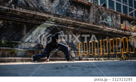 A energetic, cool Asian hiphop guy in fashionable clothes is practicing breakdance on the street. A energetic, cool Asian hiphop guy in fashionable clothes is practicing breakdance on the street. 112313295