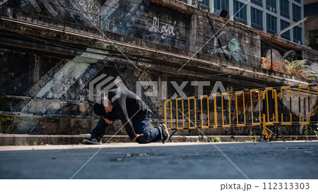 A talented, cool Asian male hiphop dancer in stylish clothes is breakdancing on the street. A talented, cool Asian male hiphop dancer in stylish clothes is breakdancing on the street. 112313303