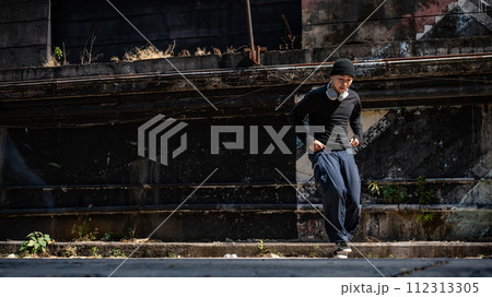 A cool, active Asian male hiphop dancer in fashionable clothes is breakdancing on the street. A cool, active Asian male hiphop dancer in fashionable clothes is breakdancing on the street. 112313305
