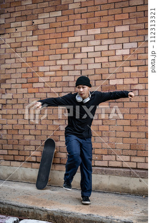 A cool Asian man in fashionable clothes is dancing on the street, practicing his breakdance outdoors 112313321