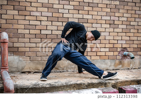A cool Asian male hip-hop breakdancer is dancing on the street, showcasing his talented movements. A cool Asian male hip-hop breakdancer is dancing on the street, showcasing his talented movements. 112313398
