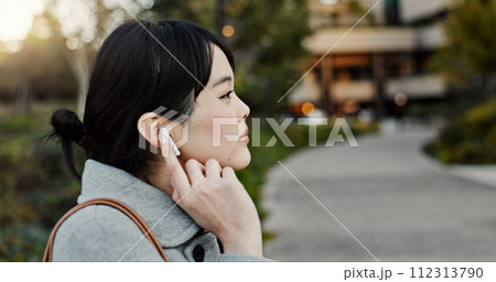 Japanese woman, earphones and walk in city with listening, music and streaming subscription on road. Girl, person and audio tech for podcast, radio and sound with travel on metro sidewalk in Tokyo 112313790