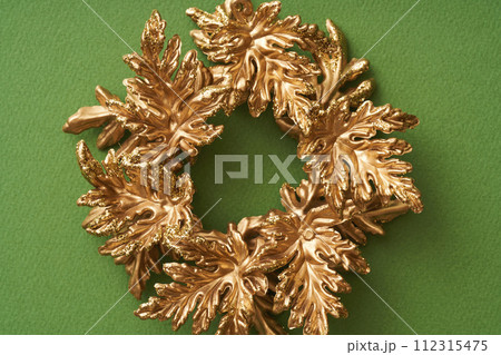 緑色の背景に置かれた金色のクリスマスリース 緑色の背景に置かれた金色のクリスマスリース 112315475