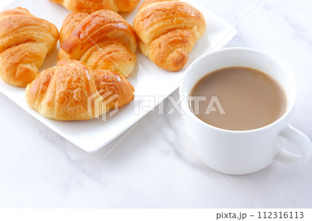 焼きたてのクロワッサンと淹れたてのカフェ・オ・レが用意された朝食のテーブル 112316113
