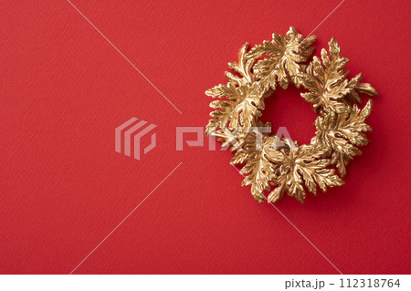 赤い背景に置かれた金色のクリスマスリース 赤い背景に置かれた金色のクリスマスリース 112318764