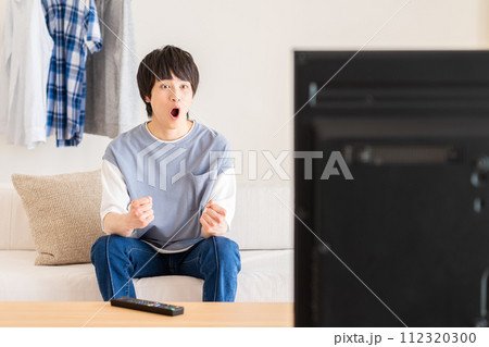 リビングでテレビを見る若い男性 リビングでテレビを見る若い男性 112320300