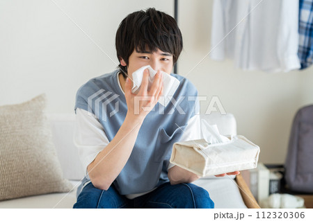 リビングで鼻をかむ若い男性 リビングで鼻をかむ若い男性 112320306