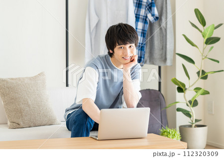 リビングでパソコンを見る若い男性 112320309