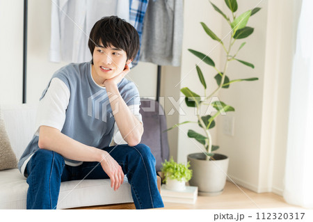 リビングでくつろぐ若い男性 112320317