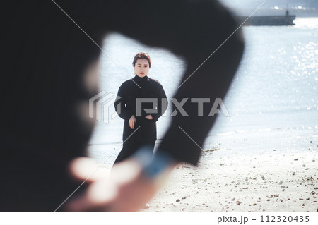 海辺で男性の後ろに立つ女性 112320435